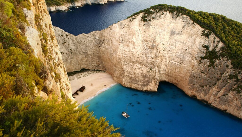 an aerial view of a beach with a boat in the water